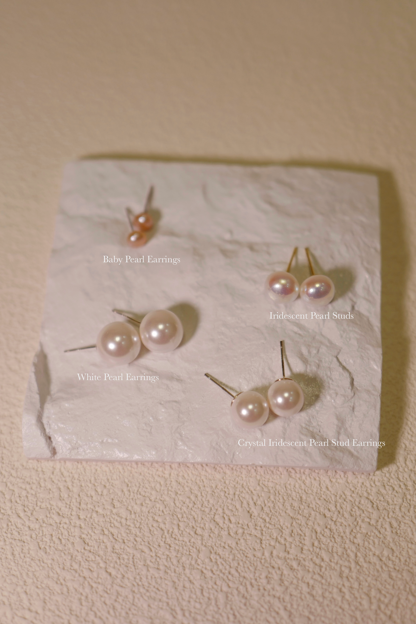 Four Different Pearl Earrings Placed On A White Plate